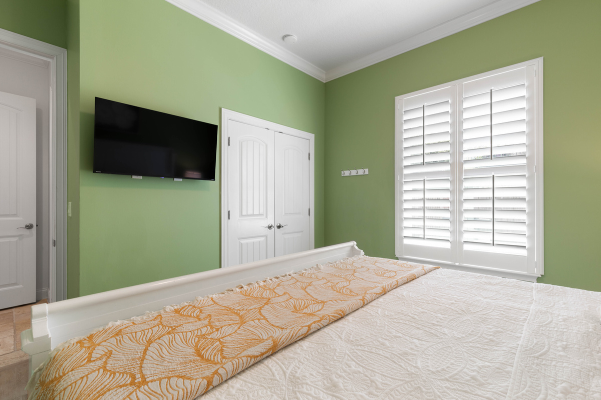 Wall-mounted TV and a double closet in the Green Suite, with shutters to dim the light for an afternoon nap.