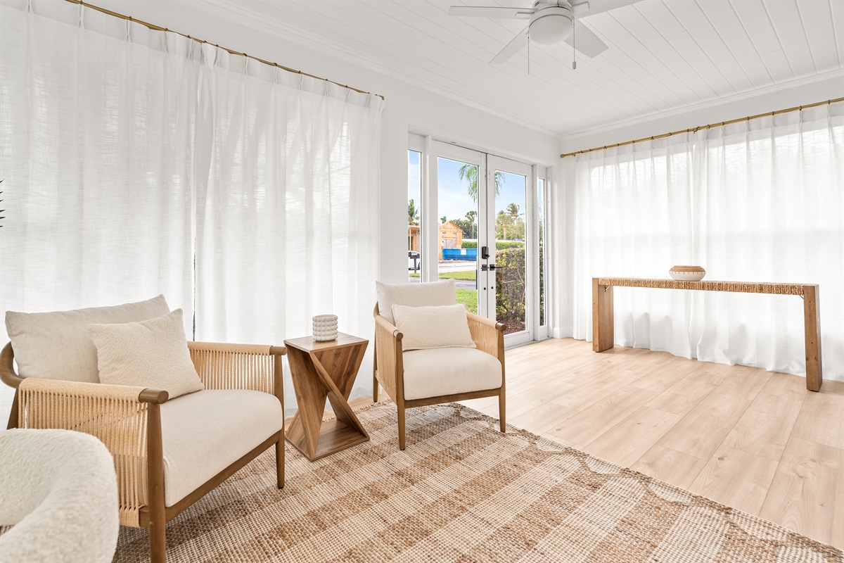 Sunlight pours through airy curtains, creating the perfect coastal nook to sip coffee and unwind.