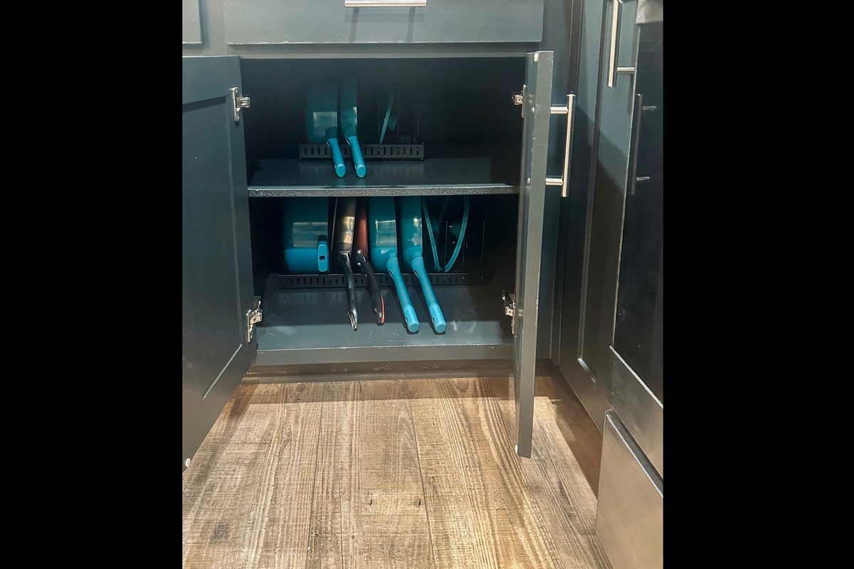 Kitchen cabinet organized with a full set of pots and pans to support everyday cooking and extended stays.