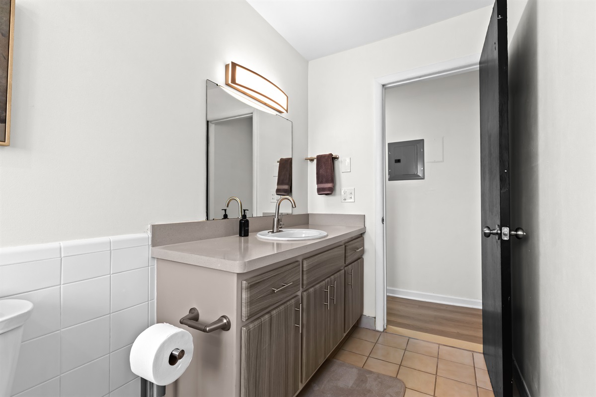 Clean bathroom with a wide vanity, large mirror, and bright lighting.