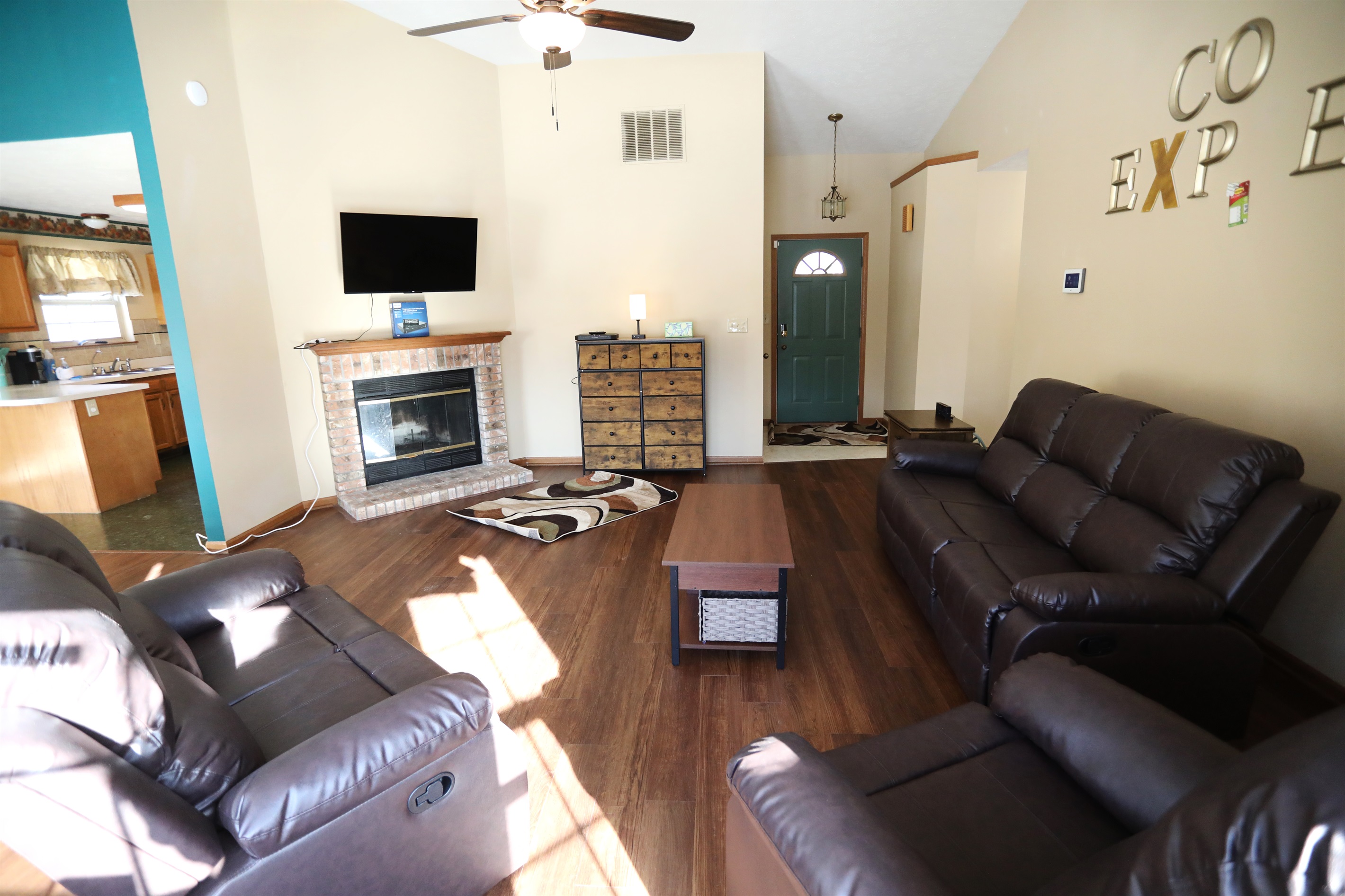 Living Room show Roku TV, fireplace, reclinable single seat, reclinable loveset, and reclinable sofa, coffee table, with foyer in the background