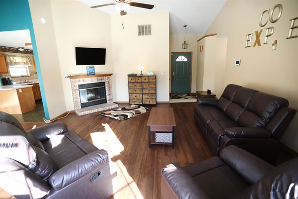 Living Room show Roku TV, fireplace, reclinable single seat, reclinable loveset, and reclinable sofa, coffee table, with foyer in the background