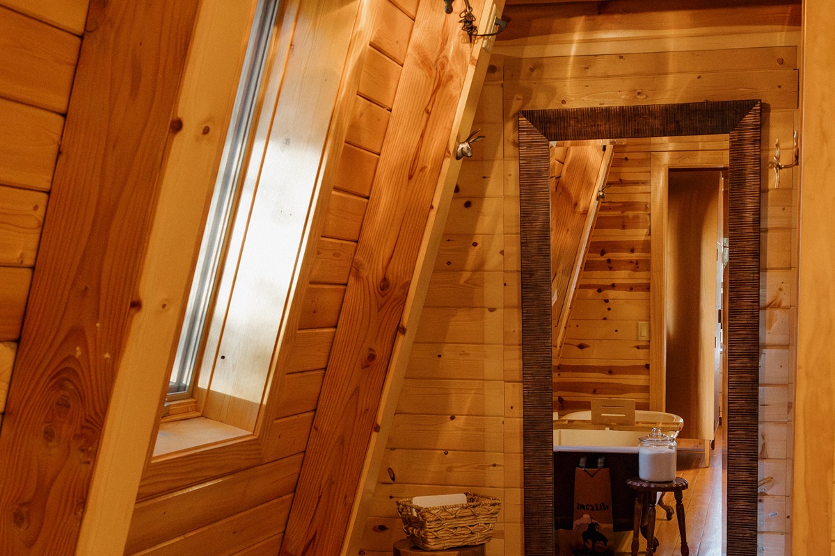 The spa-like bathroom at Poppywood Pines features a clawfoot tub, skylight, and full-length mirror. This gothic western Show Low A-frame offers luxurious comfort with rustic charm, perfect for unwinding after White Mountains hiking, fishing, and adventures