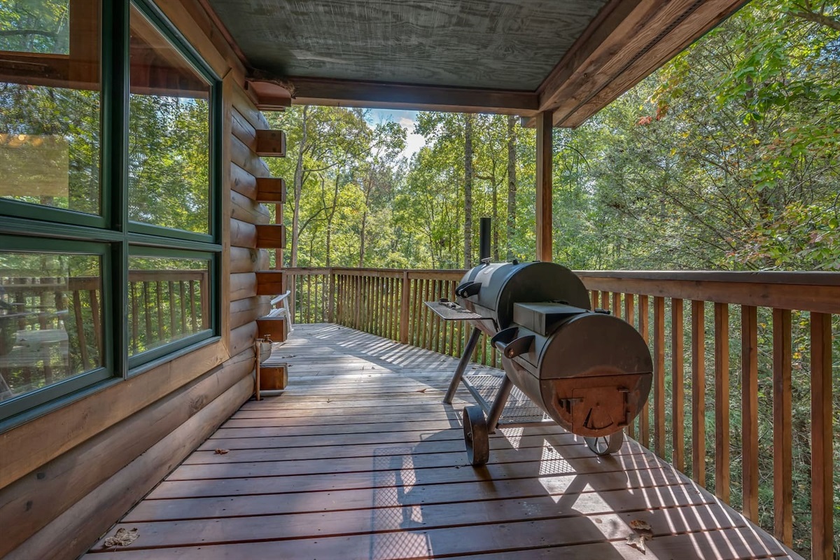 Side deck with large charcoal frill/smoker/log picnic table and corn hole games