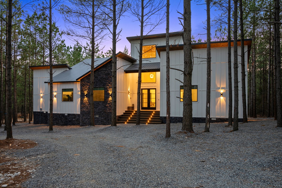 As you arrive, the modern cabin exterior stands beautifully among the towering pines, offering a warm and inviting welcome from the moment you pull in.