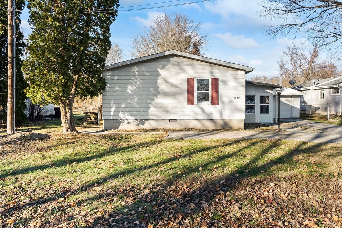 Welcoming front view of the home with mature trees and a private driveway.