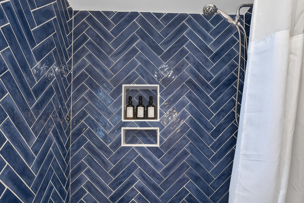 Beautiful walk-in shower featuring stylish tile and a built-in niche for toiletries.