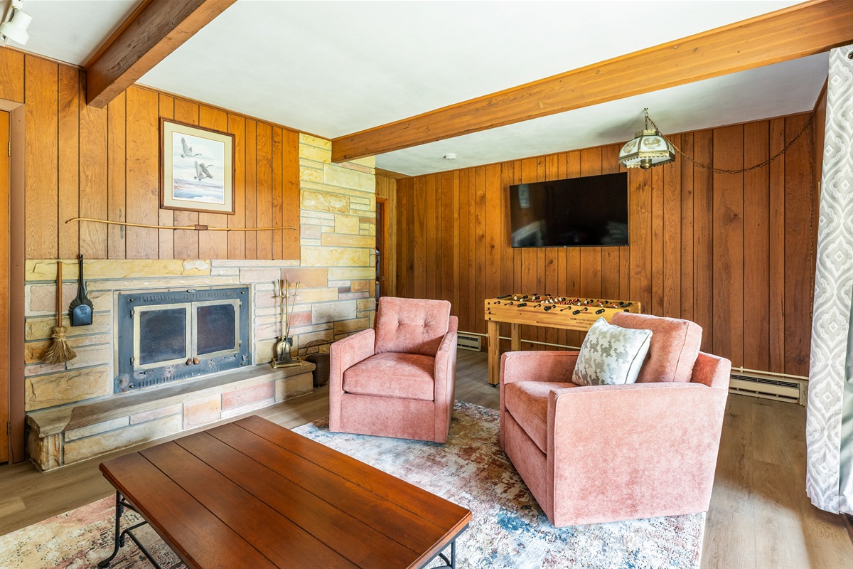 Bright and inviting lounge featuring comfy chairs, a large flat-screen TV, and sliding doors that open to the outdoors for a seamless indoor-outdoor retreat.