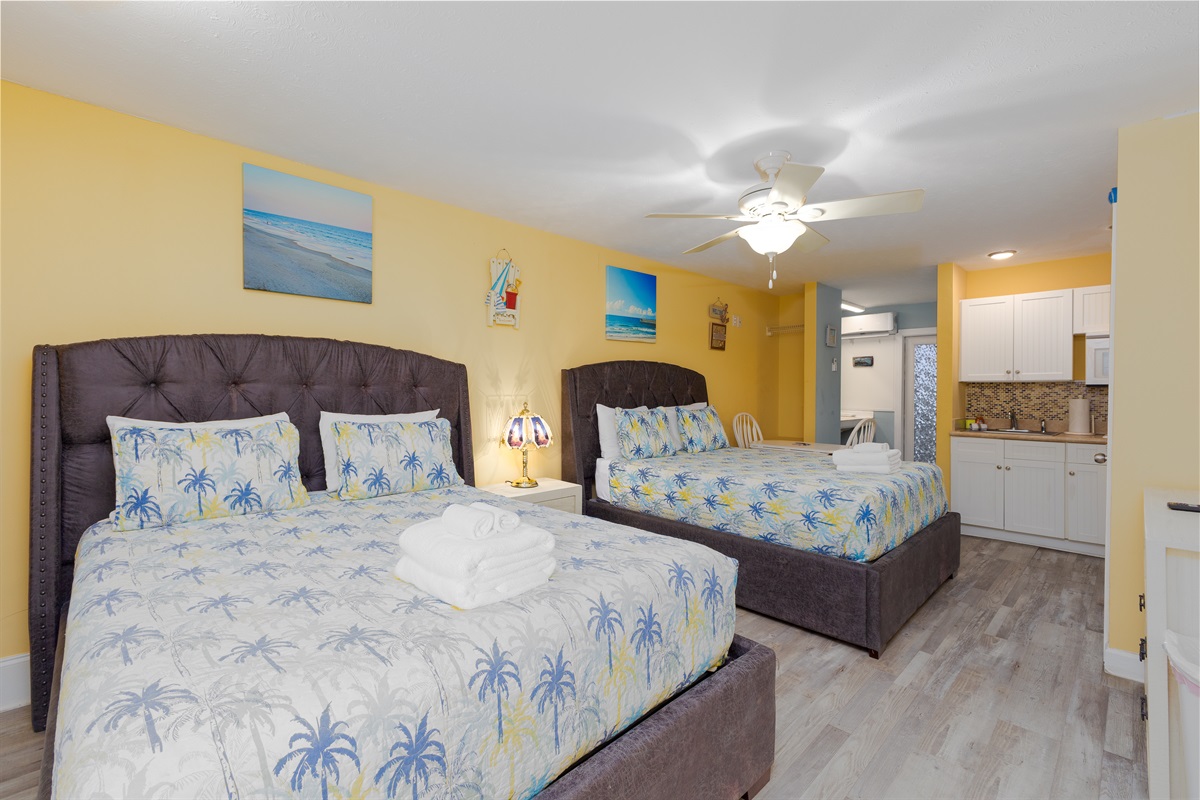 Spacious open-concept room featuring two Queen beds, cozy coastal d&eacute;cor, and easy access to the kitchenette