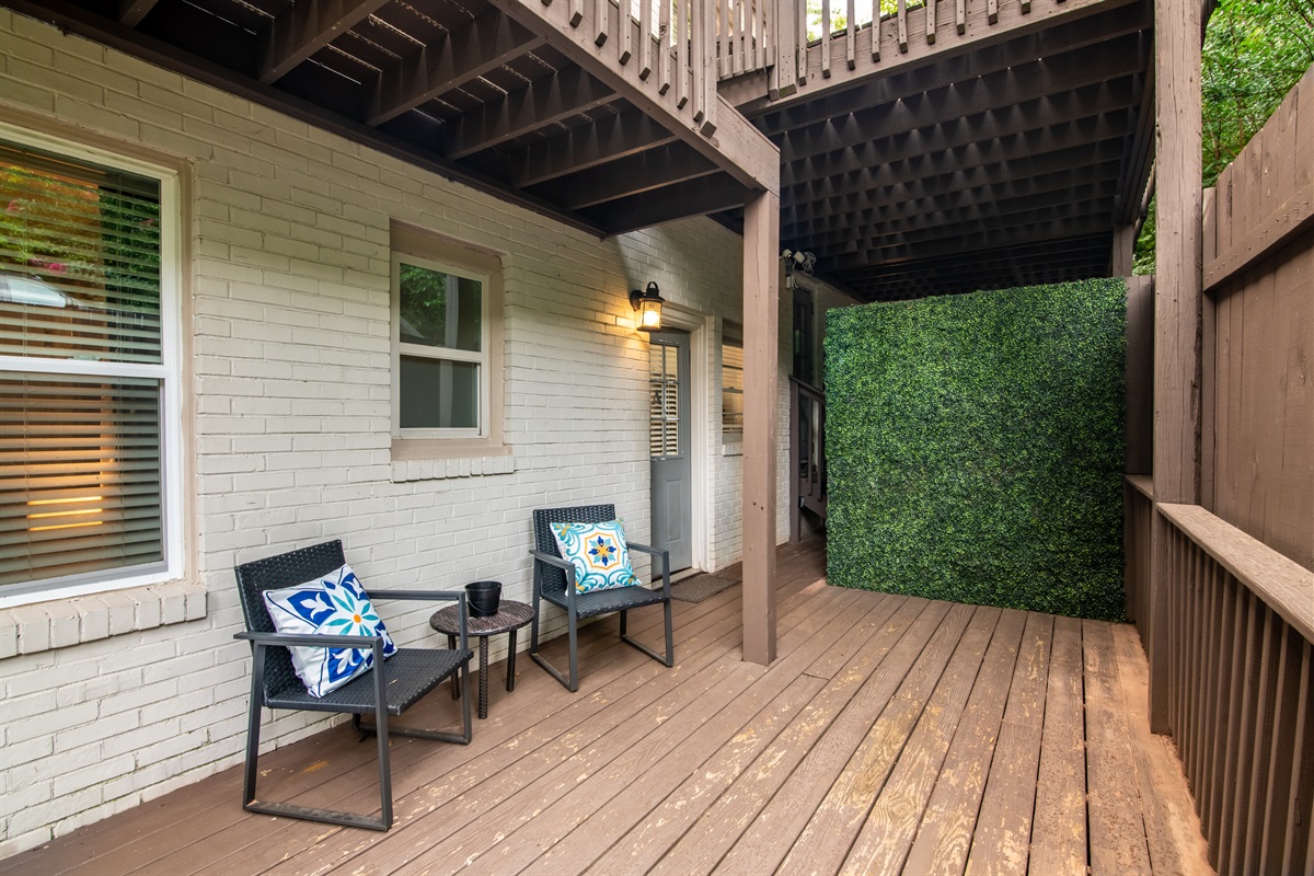 Relaxing patio space under a covered deck, featuring cozy seating and a private outdoor vibe—perfect for morning coffee or evening chats.