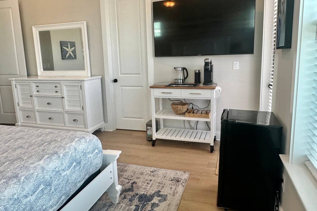 The first-floor primary bedroom offers added convenience with a private coffee bar and mini fridge, perfect for slow mornings or late-night refreshments.