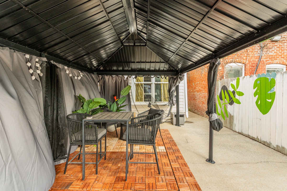 Outdoor Oasis: Enjoy al fresco dining in a stylish shaded retreat adorned with lush greenery!
