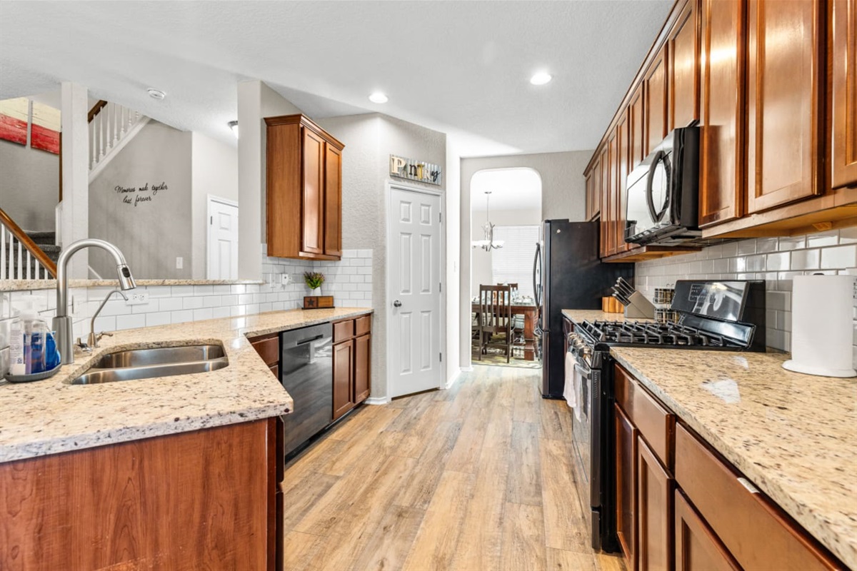 Spacious kitchen with full fridge/freezer combo, stainless steel oven, microwave, gas cooktop, and all cooking tools, pots, pans, dishes, and cutlery included.