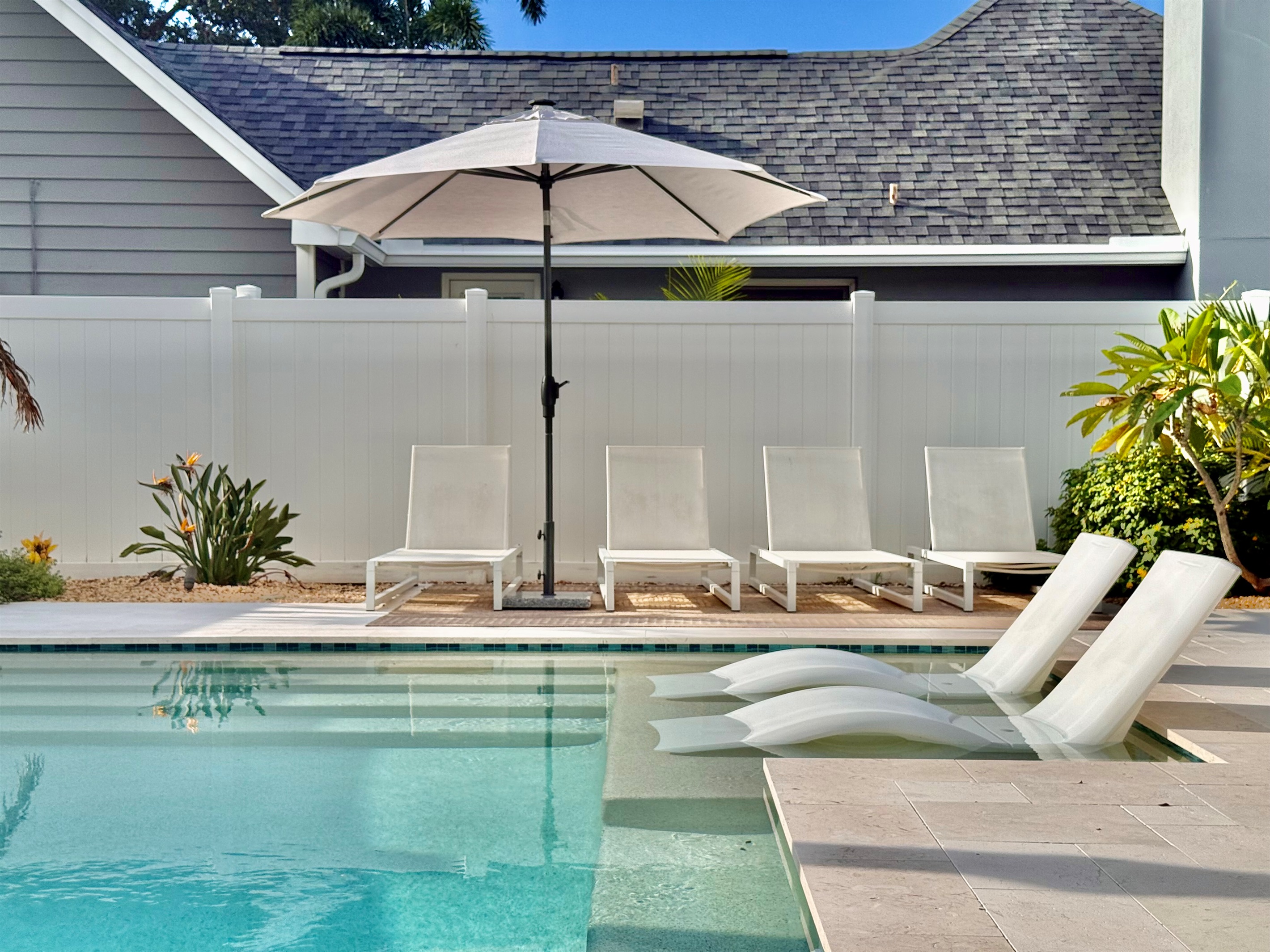 Dive into the turquoise waters of your heated pool, surrounded by privacy fencing and tropical plants.