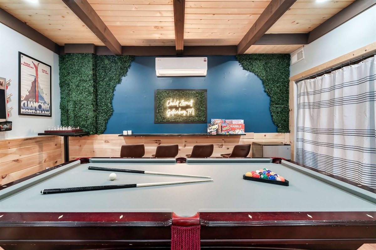 The lower level basement, with an exterior access door features 75" smart TV, pool table, ping-pong table topper, mini fridge, cornhole boards, 2 arcade games, a pull-out sofa bed, and a wood-burning fireplace. There is a full bathroom on this level.