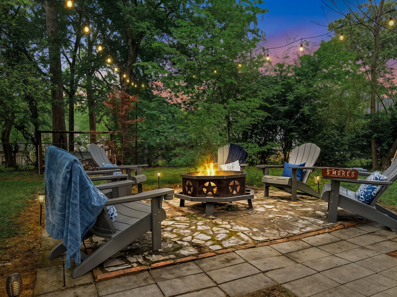 Gather at the firepit as the string lights flick on — marshmallows toasting, the whole group pulled into one circle. After a day at Oaklawn, this is where the night lands.