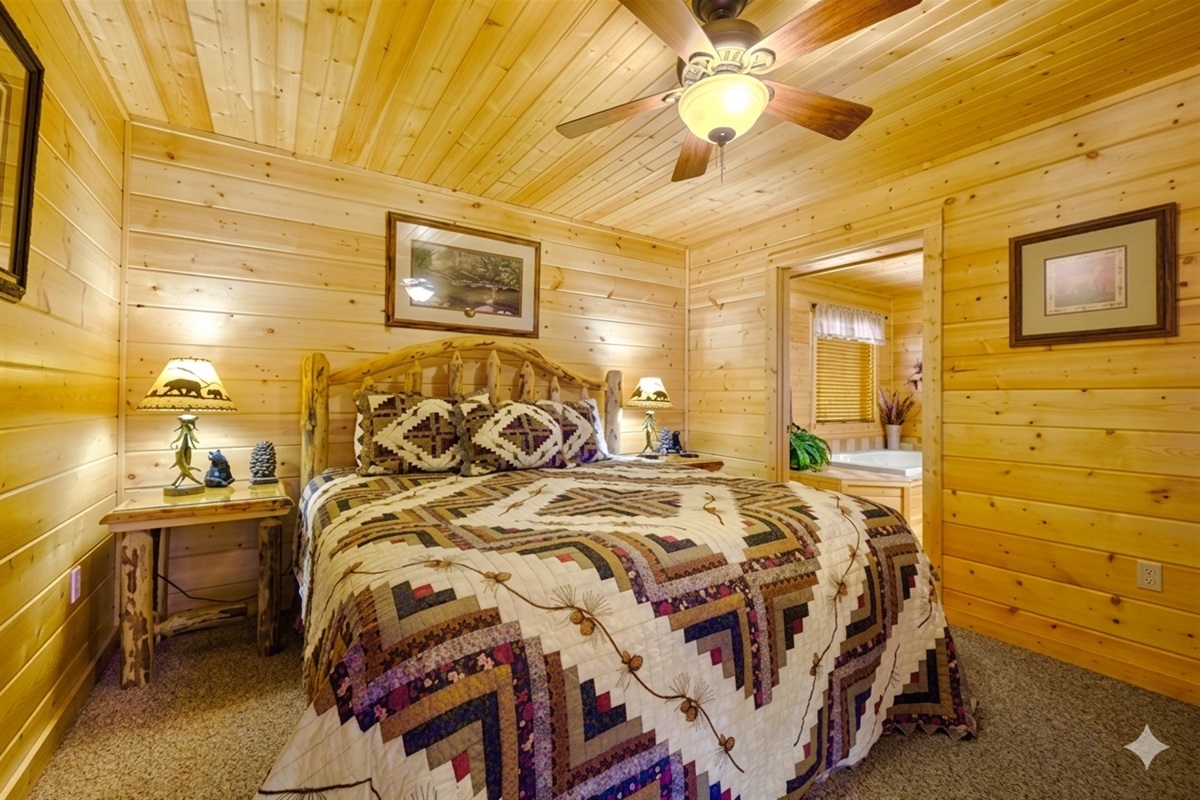Bedroom #1 - Nestled in golden wood tones, this king bedroom feels like a cozy forest retreat. Drift off under the soft glow of rustic lamps after a day of mountain adventures.