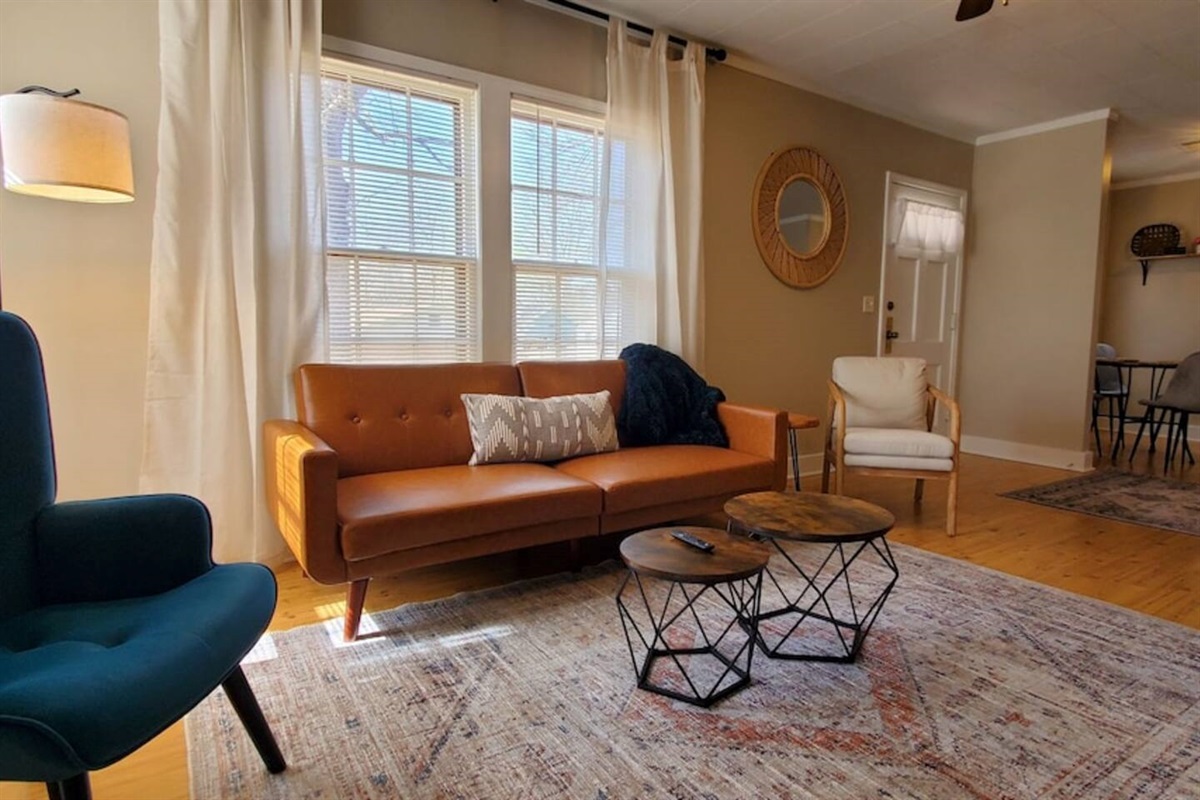 Cozy and stylish living area with comfy seating, smart TV, and modern decor. Enjoy a spacious layout with dining space, natural light, and a fully equipped kitchen—perfect for relaxing or working remotely.