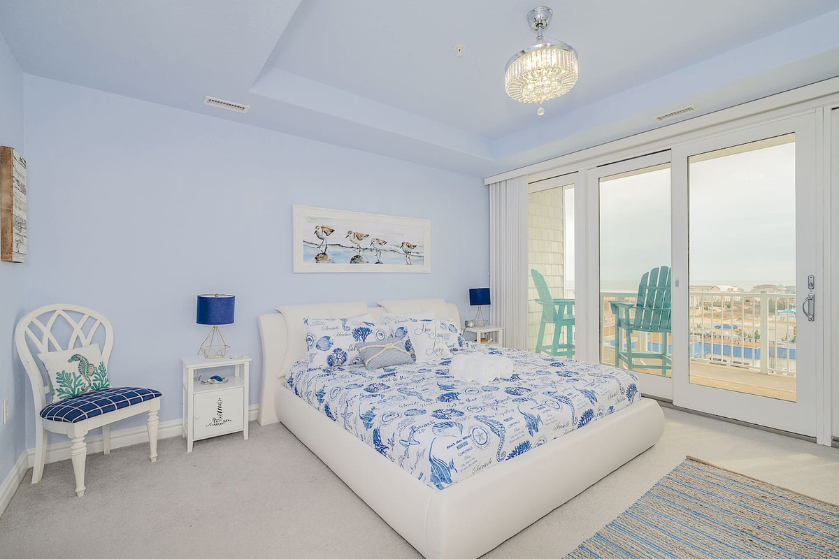 Wake up to breathtaking beach views in this cozy coastal king bedroom  Sliding doors open to your private balcony with Adirondack chairs perfect for morning coffee ☕️