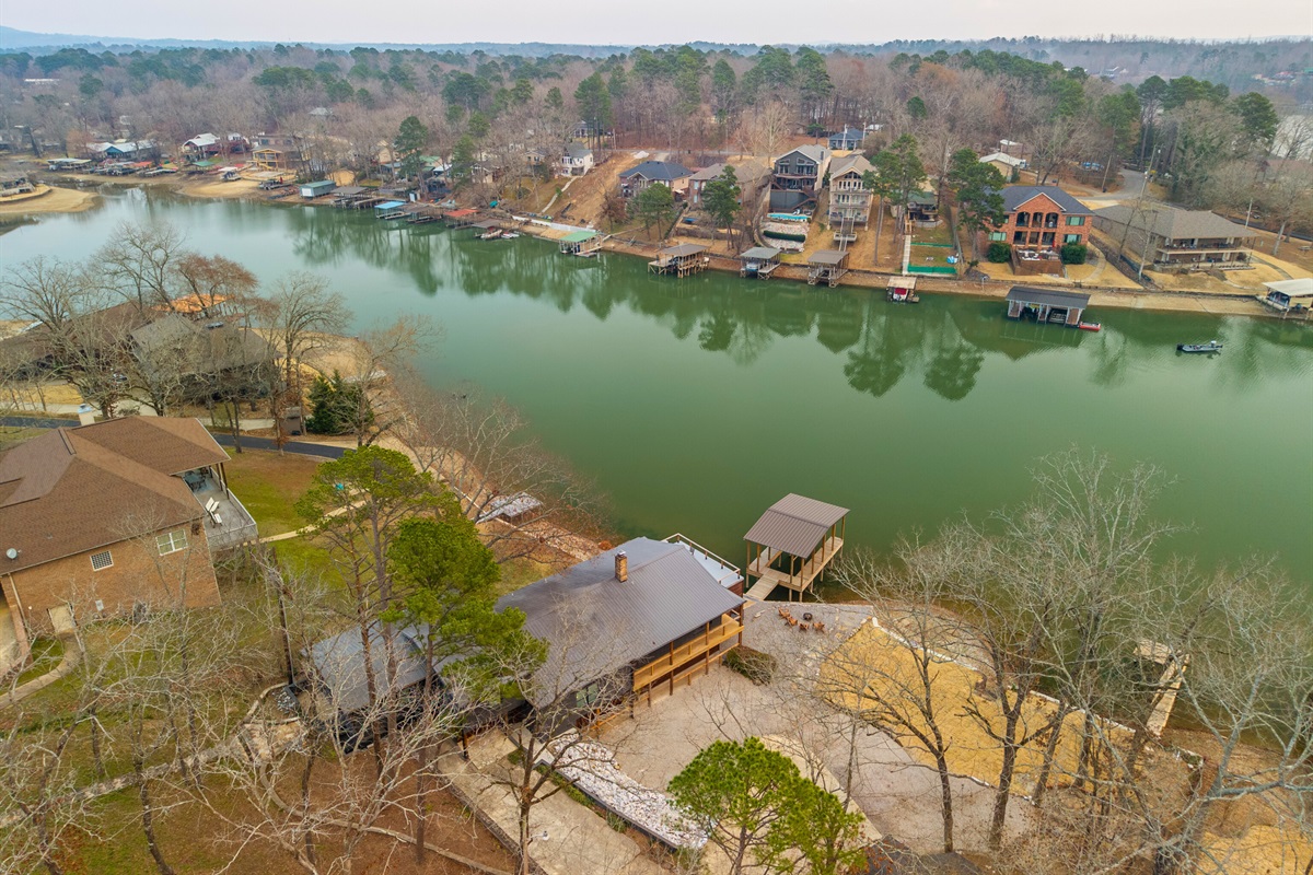 Captured from above, the aerial view reveals the full lakeside setting, with the home, dock, and calm waters of Lake Hamilton surrounding the property.
