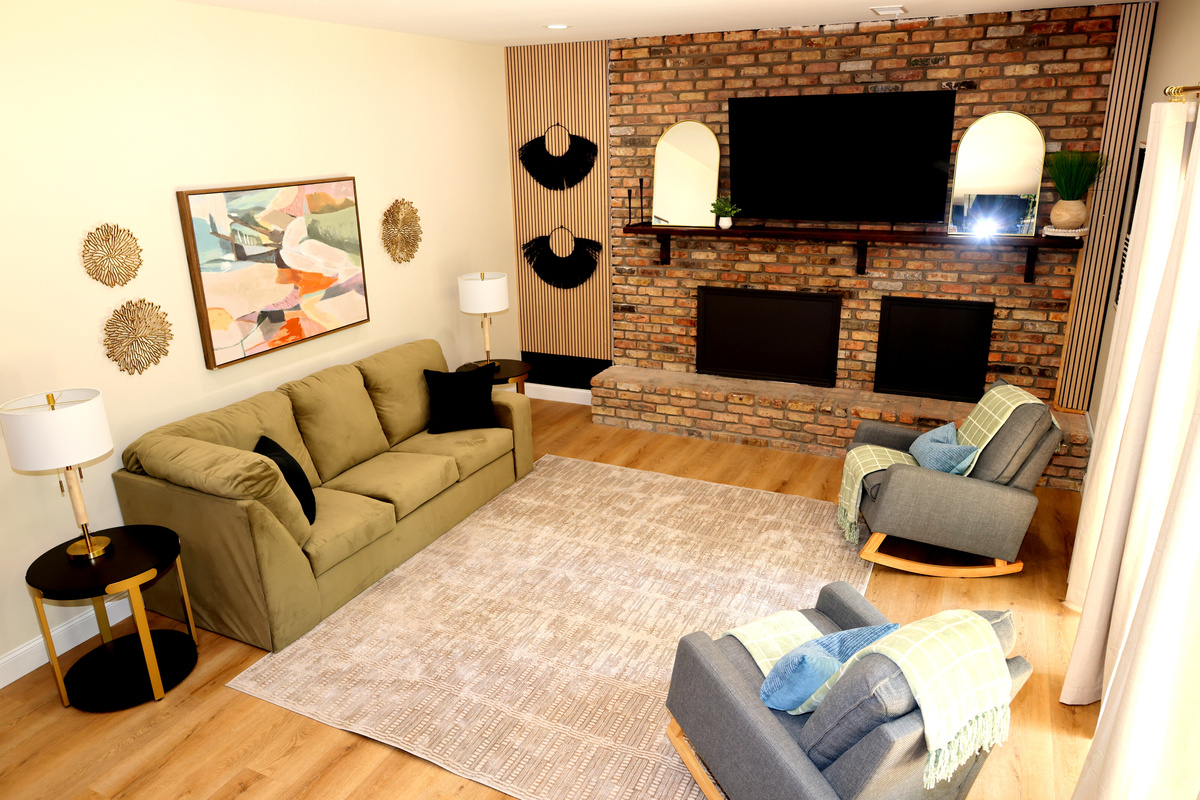 Cozy lower-level living room with brick fireplace feature, TV, and comfortable seating