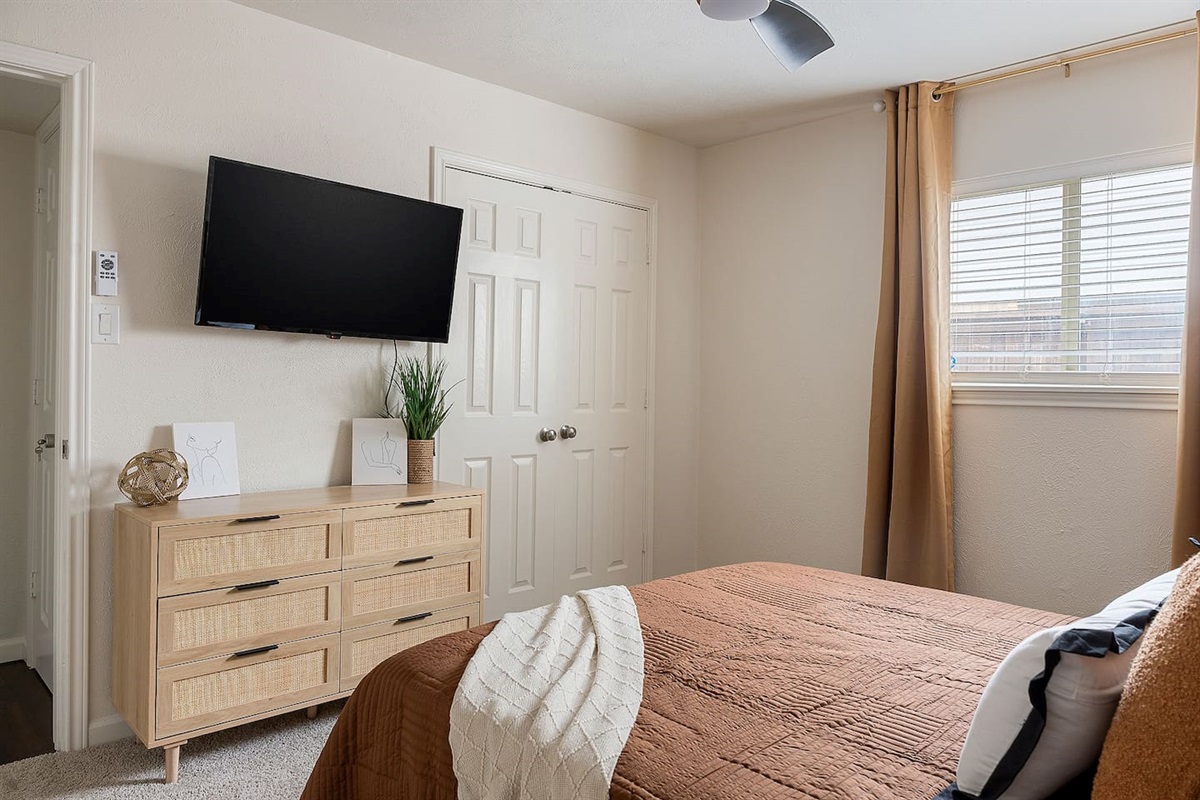 The bedroom is outfitted with a sleek dresser and a wall-mounted television, creating a modern and efficient area for leisure.