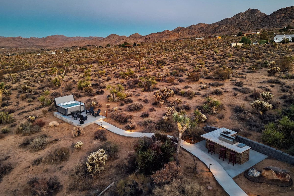 Enjoy sweeping desert and mountain views from your private backyard, complete with a hot tub, fire pit, and outdoor bar seating — the perfect spot for stargazing or sunset gatherings.