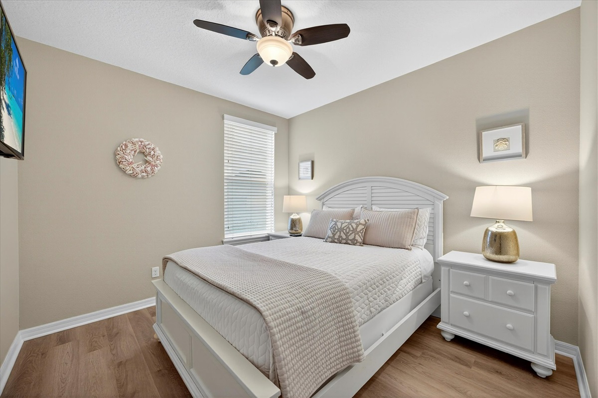 Bright guest bedroom with comfortable bedding and ceiling fan.