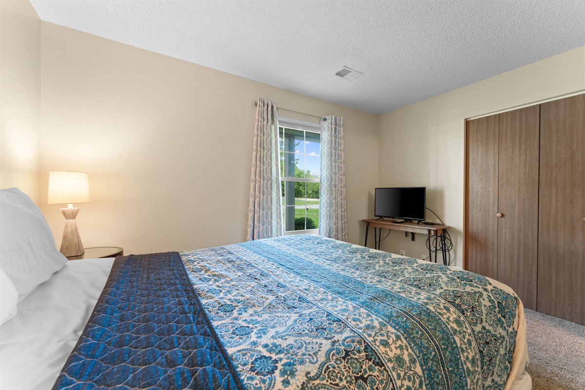 Guest bedroom with queen bed, TV, and closet—comfortable and private.