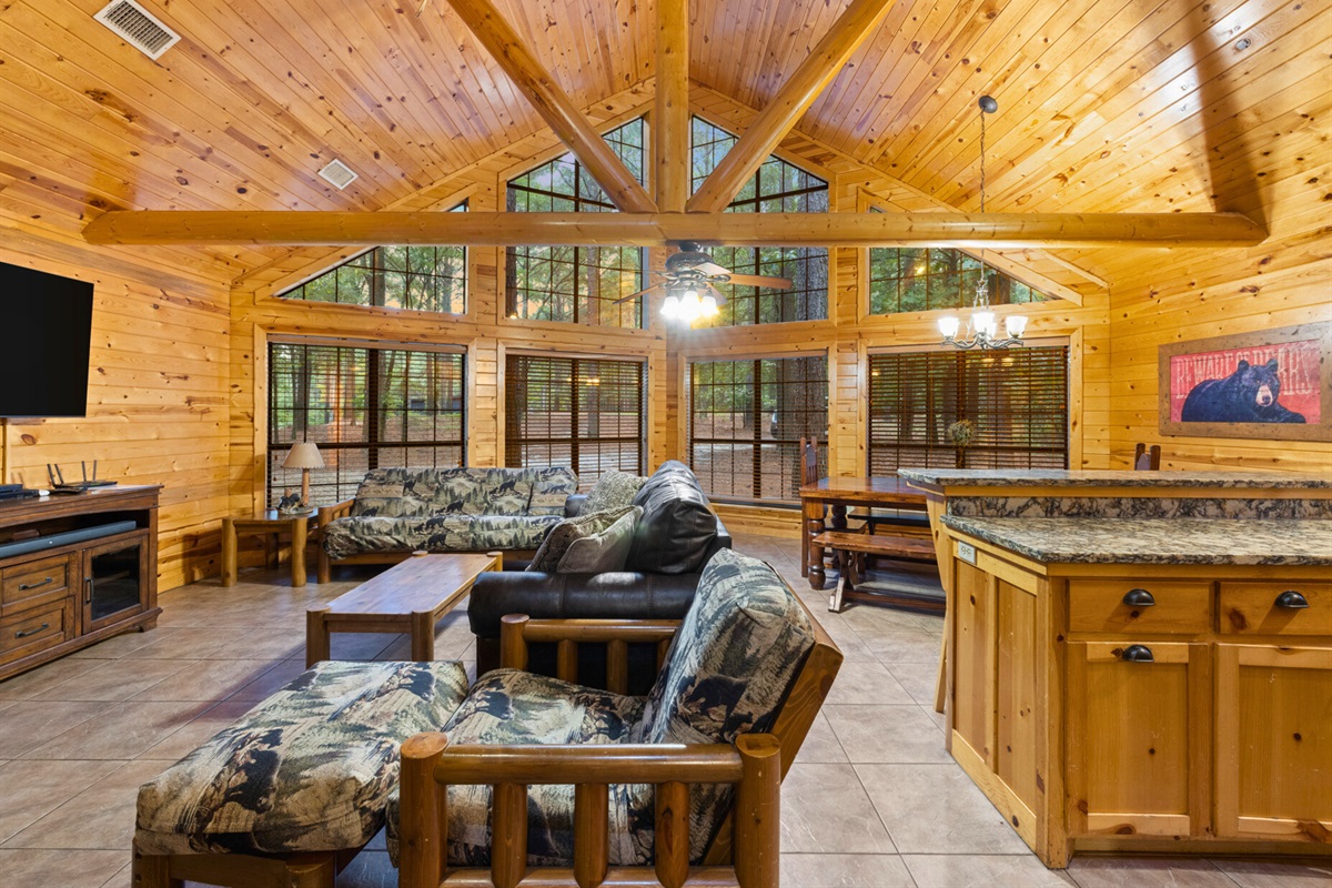 Spacious living area with high ceilings and forest views. A cozy space for movies, games, or just unwinding together.