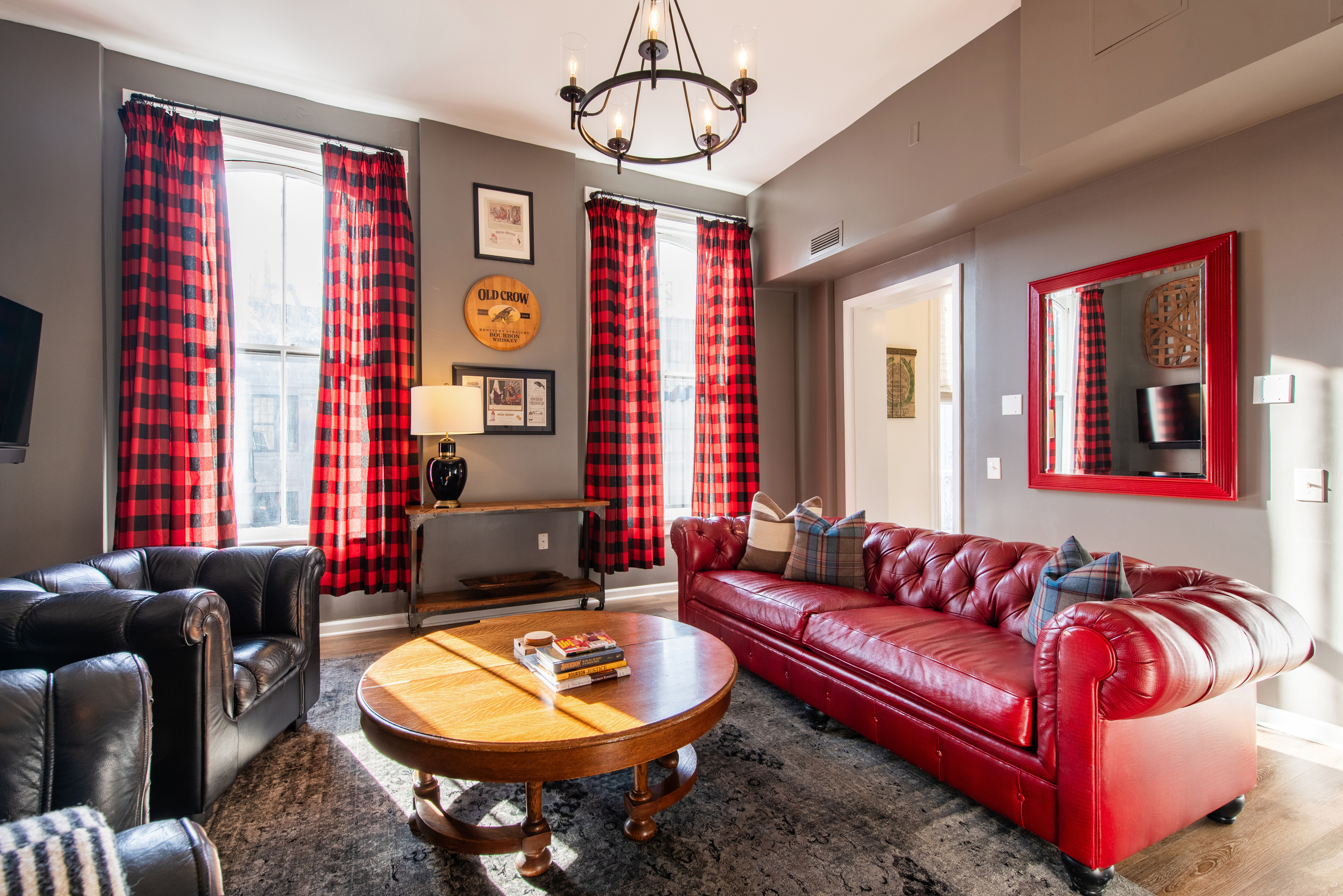 The Old Crow Suite living room, with a red leather sofa and armchairs.