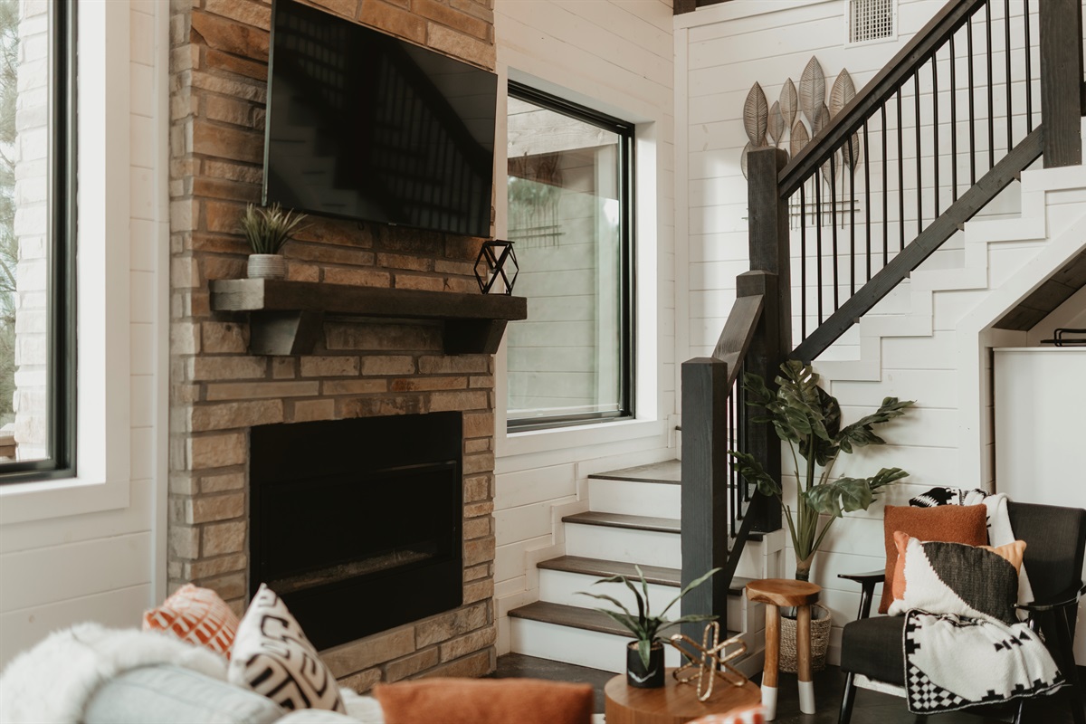 Stylish and cozy—this living room pairs a stone fireplace, plush seating, and forest views with modern cabin charm. Gather here for movie nights, fireside chats, or simply relaxing together after a day of adventure.