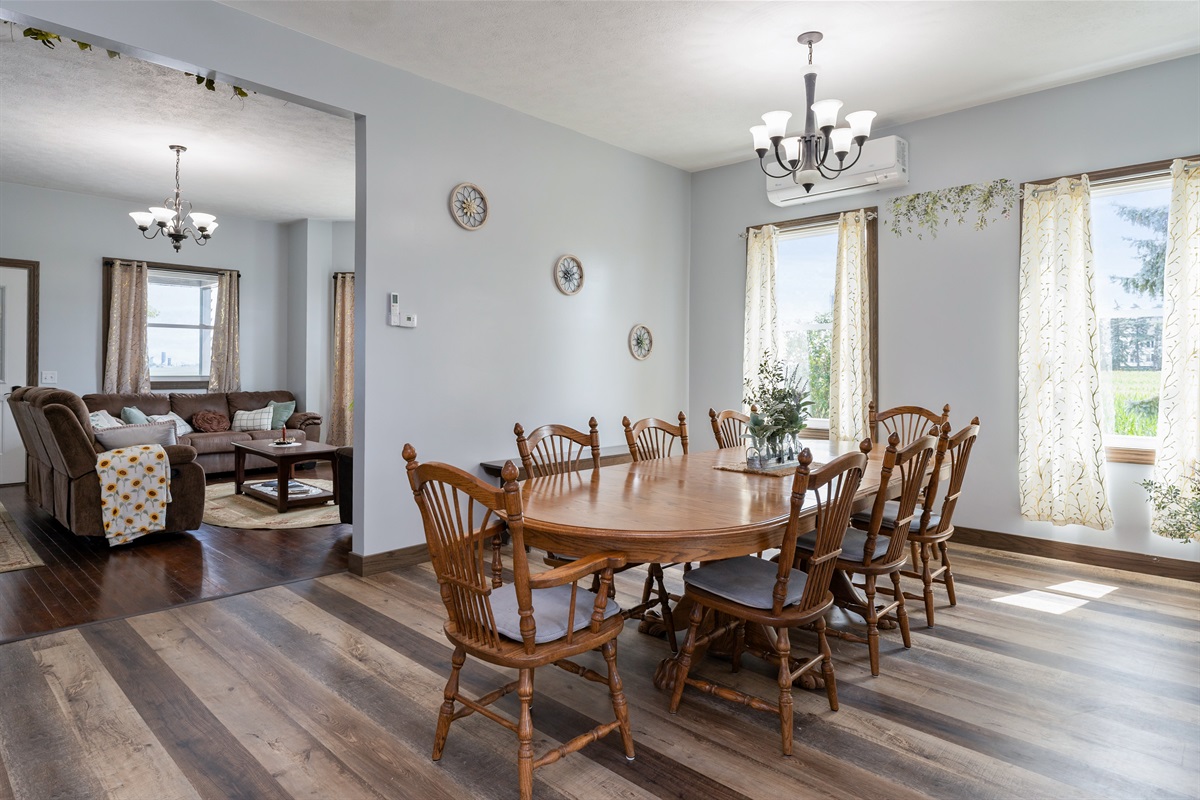 Bright and airy dining space featuring large windows, elegant curtains, and a spacious wooden table perfect for family meals or gatherings.
