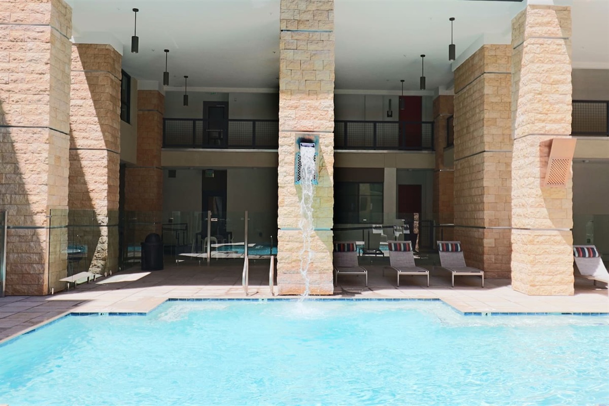 - Lounge by the pool beneath covered columns and refreshing water streams   - Relax in shaded comfort with modern lounge chairs and serene surroundings   - Ideal for cooling off, reading, or sunbathing in peaceful outdoor bliss