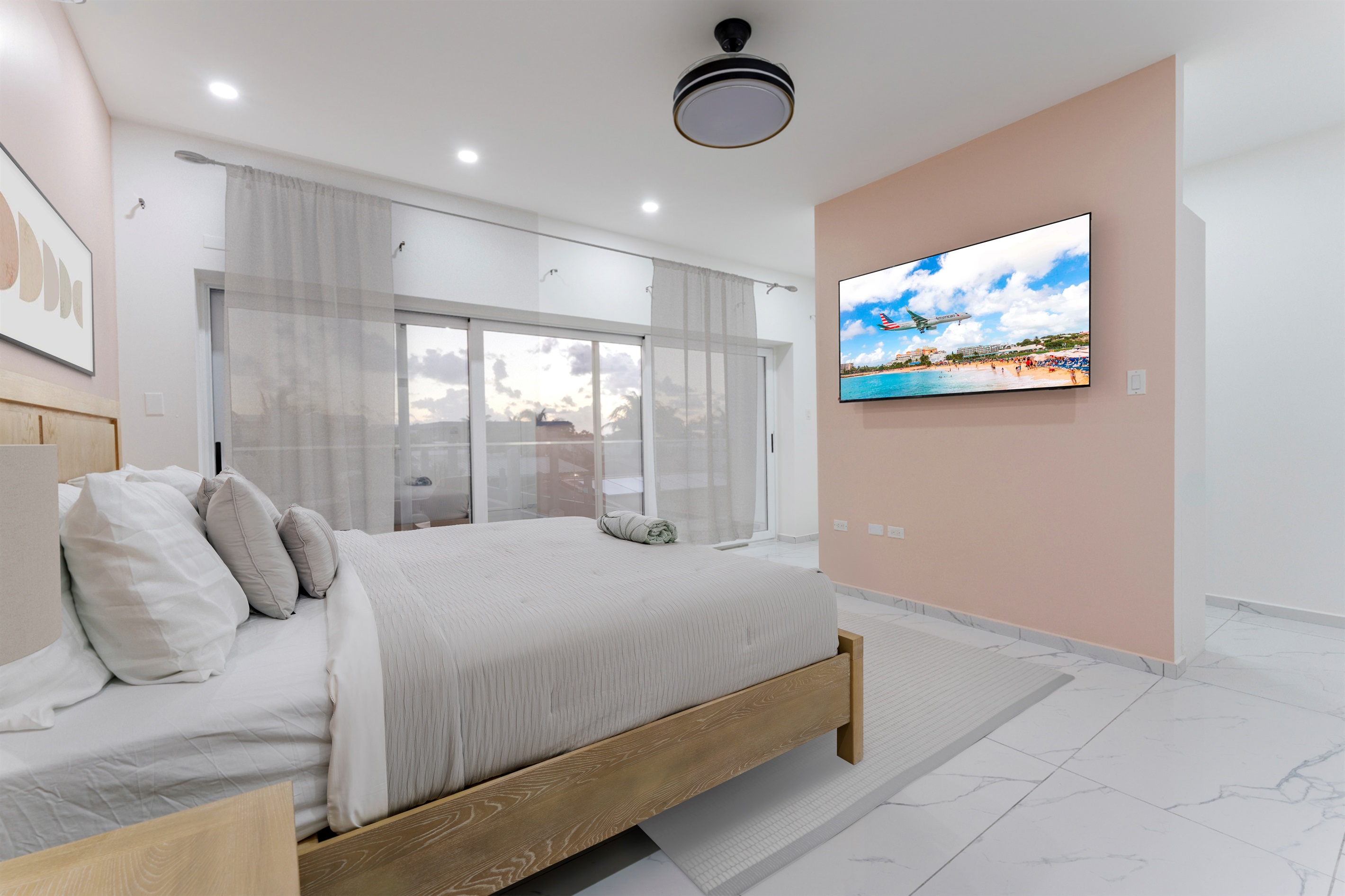 Spacious primary suite featuring a king bed, accent wall and mounted smart TV