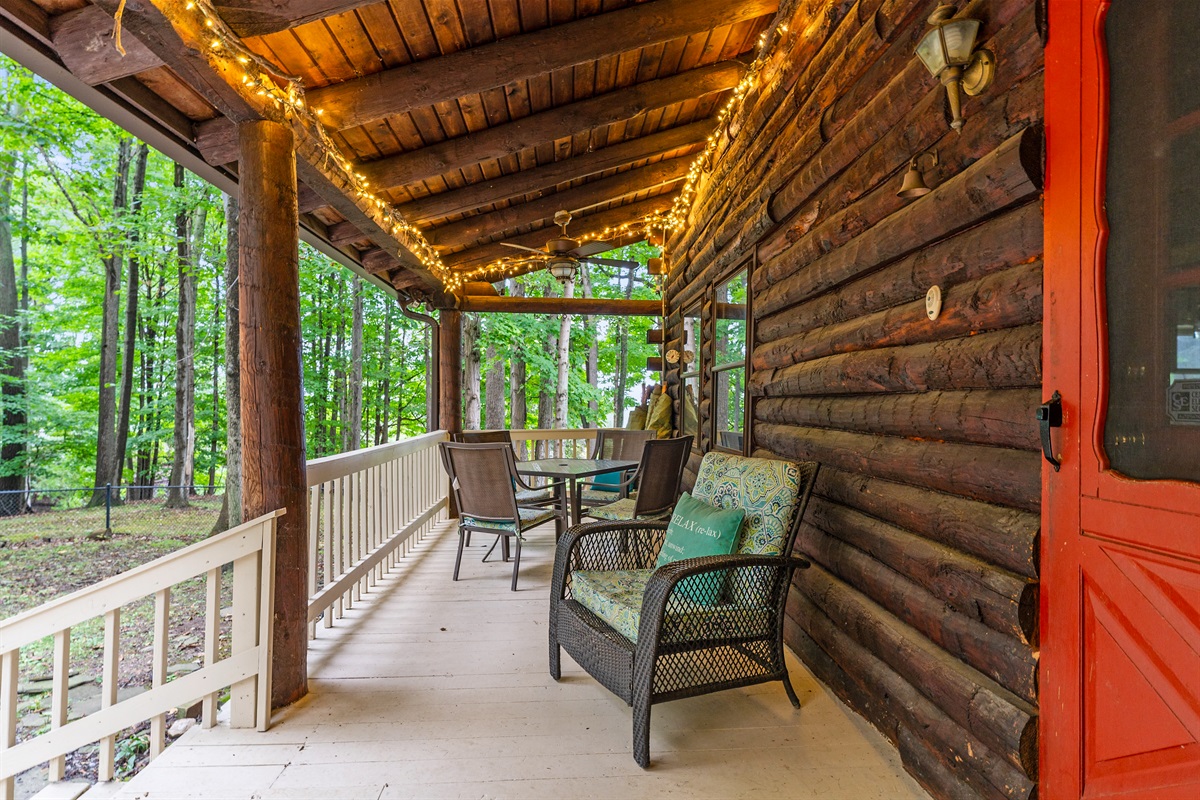 Relax on the covered porch with rocking chairs, rustic log seating, and warm ambiance perfect for morning coffee or evening sunsets.