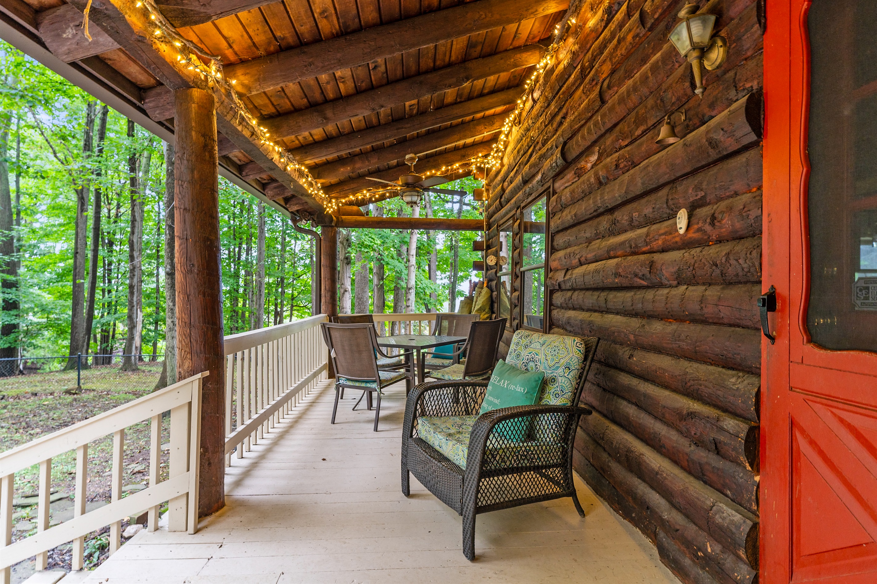 Relax on the covered porch with rocking chairs, rustic log seating, and warm ambiance perfect for morning coffee or evening sunsets.