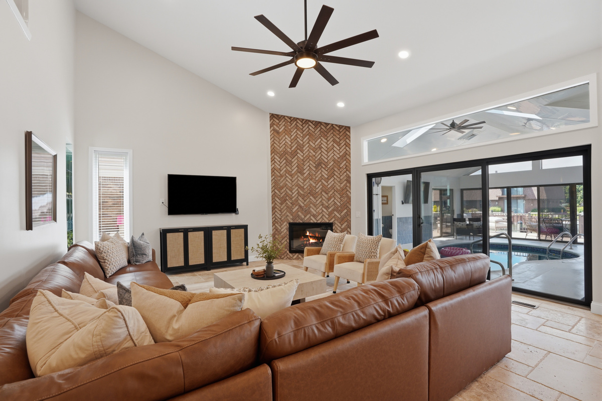 Gather in this spacious open-concept living room featuring a cozy sectional, modern fireplace, soaring ceilings, and seamless indoor-outdoor flow perfect for relaxing and entertaining.