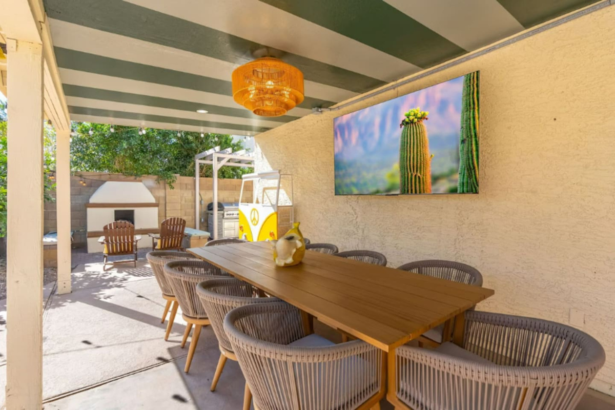 Spacious covered patio with striped ceiling, dining table, desert art, and direct pool access—seamless indoor-outdoor entertaining.