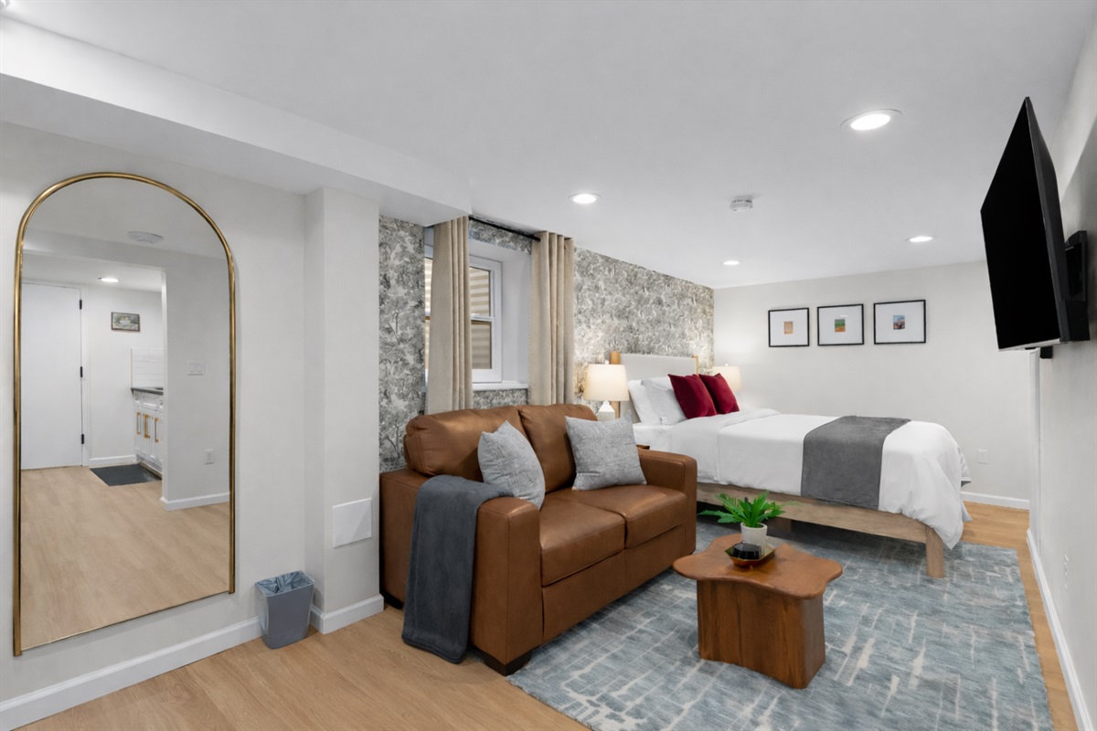 Bright, stylish studio with a plush bed, cozy seating area, smart TV, and warm finishes—designed for comfort, relaxation, and an easy stay.