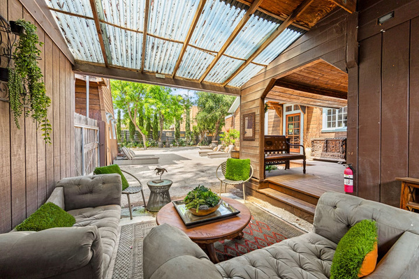 The Speakeasy by day: a covered, open-air lounge connecting the house and courtyard, with deep seating for cocktails, conversation or event-day gathering—one of several Heritage House spaces designed for lingering.
