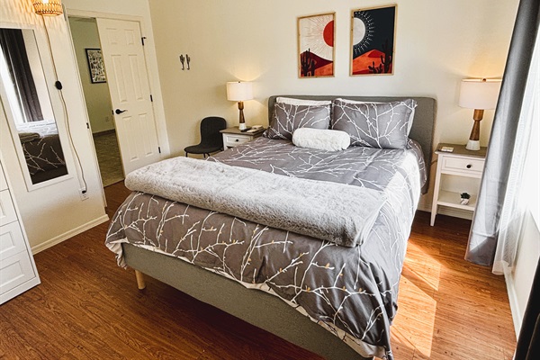 Bedroom with queen bed, smart TV, ceiling fan, blackout curtains and linens