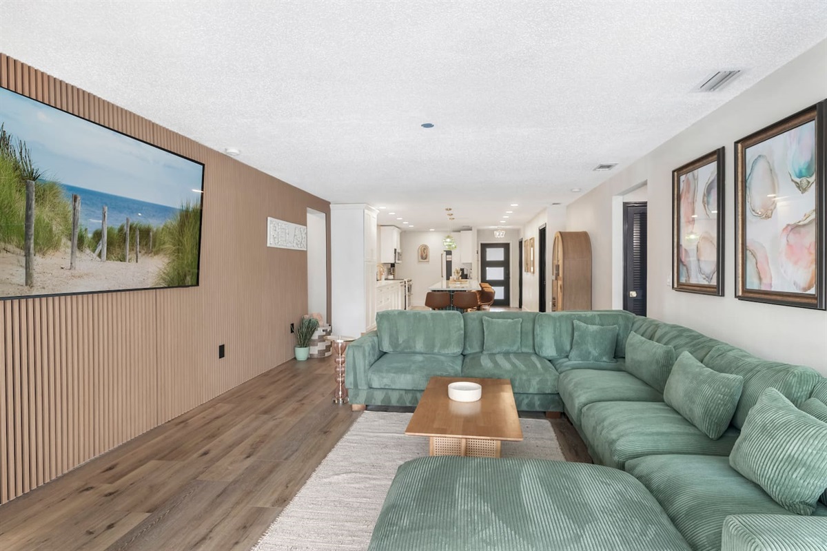 Stylish Living Room with 85-Inch TV. Acoustical accent wall, open to the kitchen and the pool 