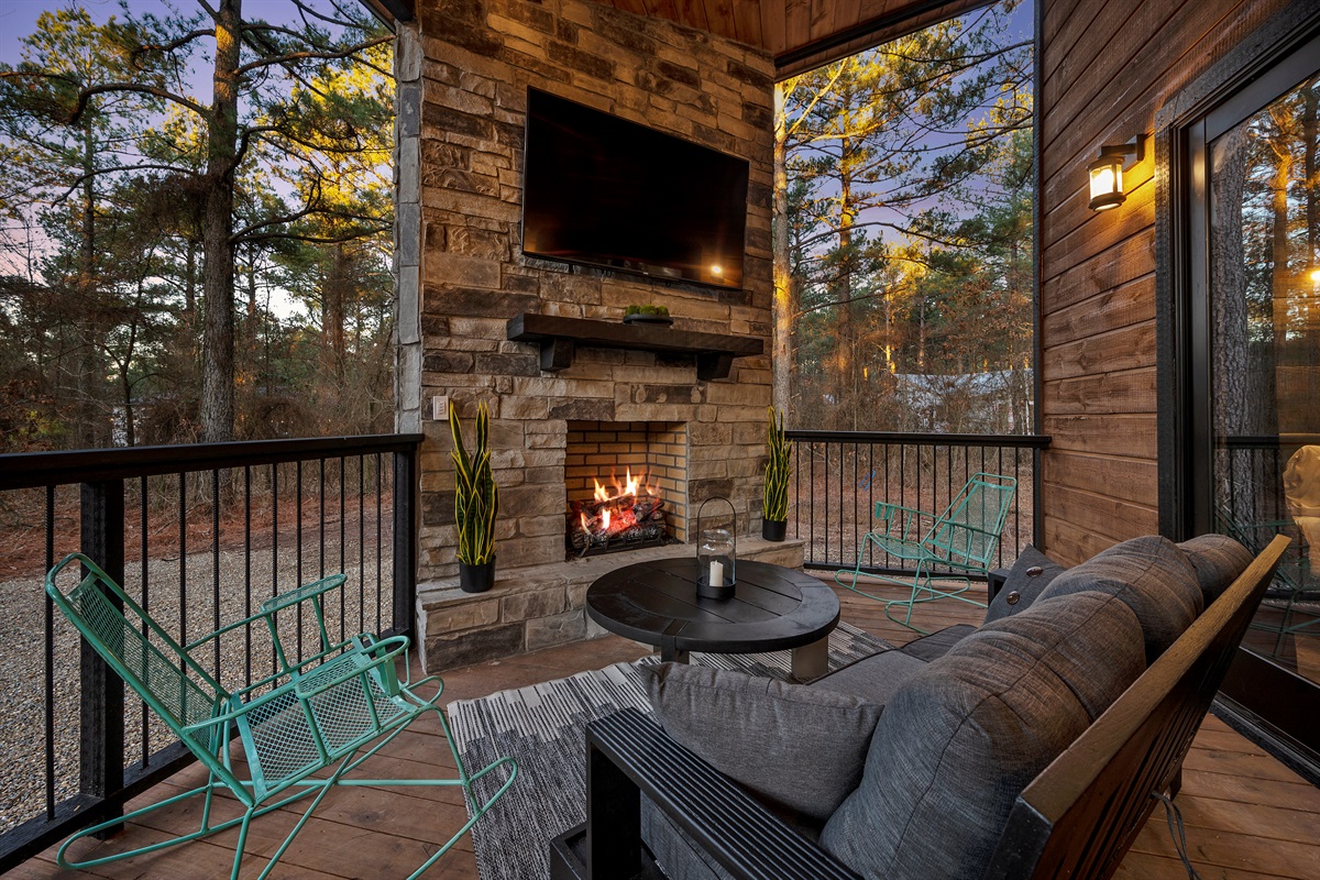 Cozy up by the outdoor fireplace as the sun sets through the trees.