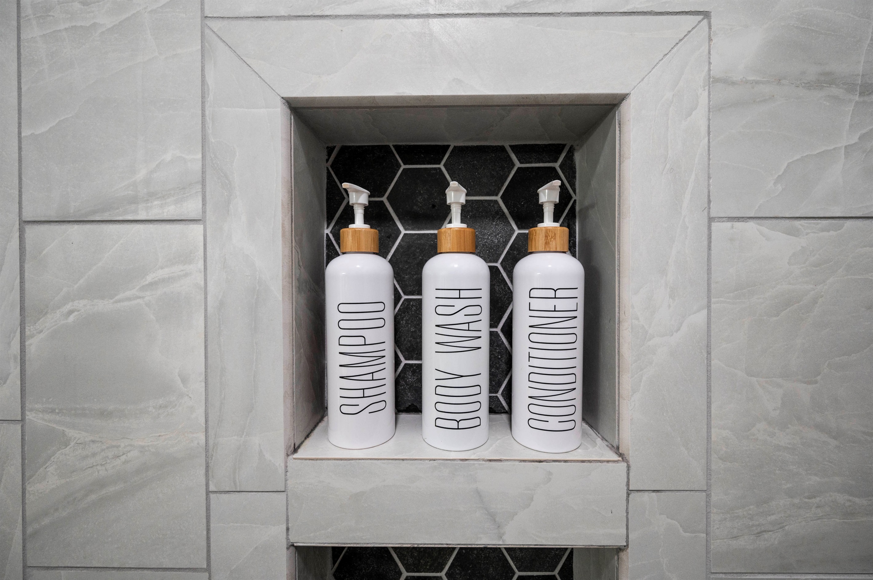 Sleek bathroom shelf with chic shampoo, body wash, and conditioner bottles.