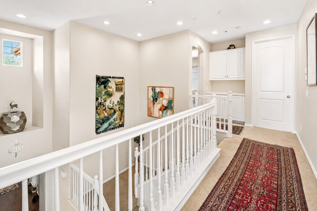 Upstairs landing with clean railings, artwork, and a hallway connecting the bedrooms.