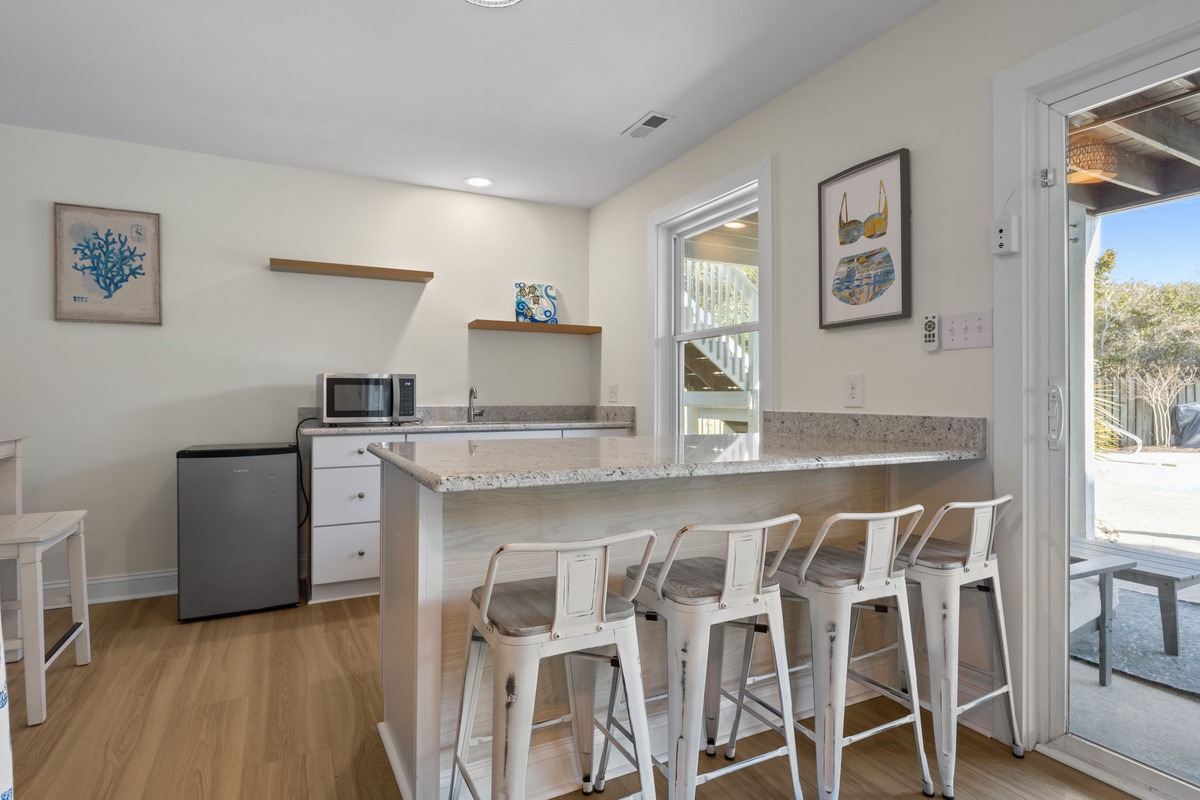 The convenient wet bar includes a mini fridge, microwave, sink, and bar seating, making snacks and drinks easily accessible without heading upstairs