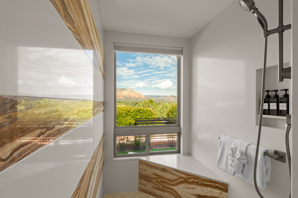Shower with a view. Our primary walk-in shower features stunning custom stone details and a massive picture window perfectly framing the iconic Sedona red rocks