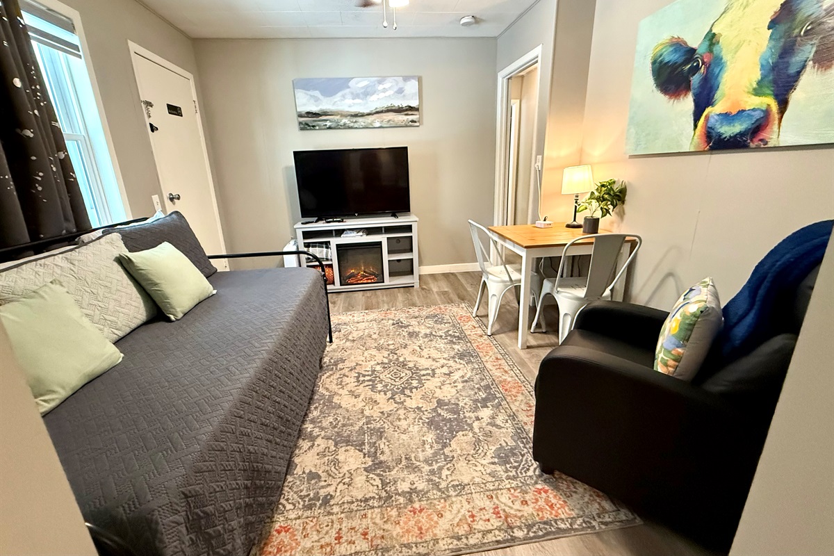 Day bed with large tv and small eating area.