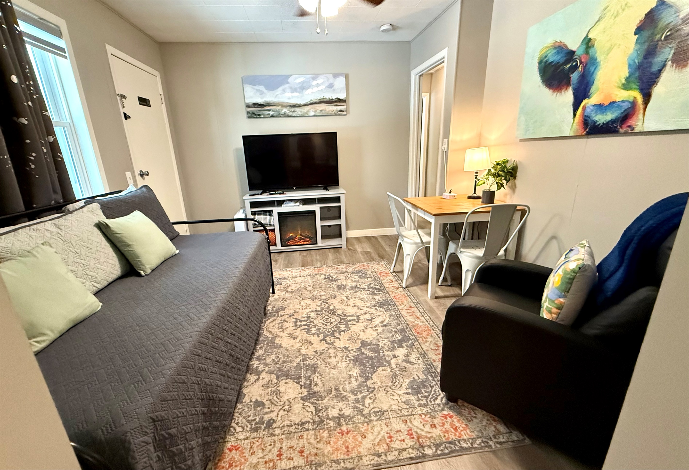 Day bed with large tv and small eating area.